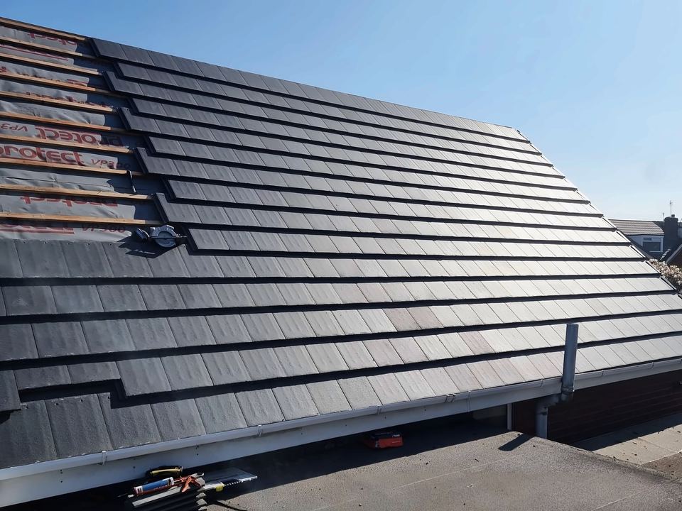 Grey tiles going on over membrane and battens, seen from the flat roof alongside