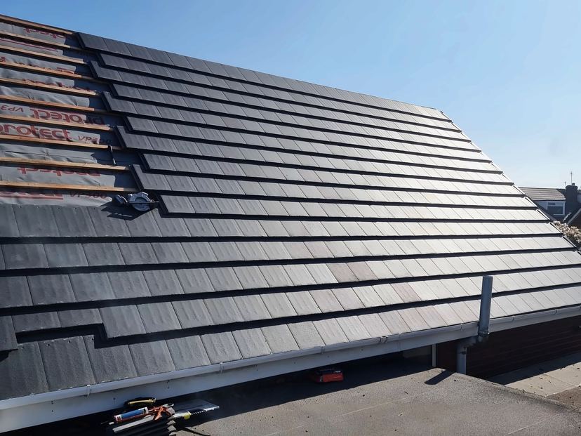 Grey tiles going on over membrane and battens, seen from the flat roof alongside