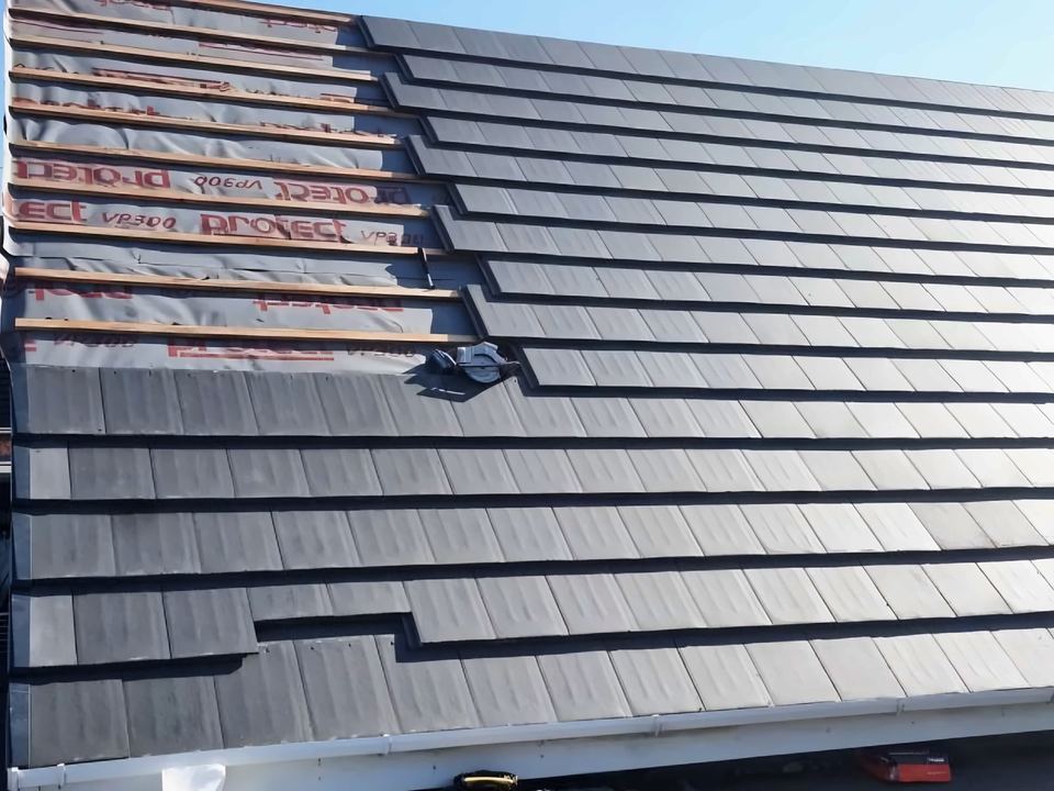 The same roof from the gable end: membrane, battens, grey tiles and white fascia