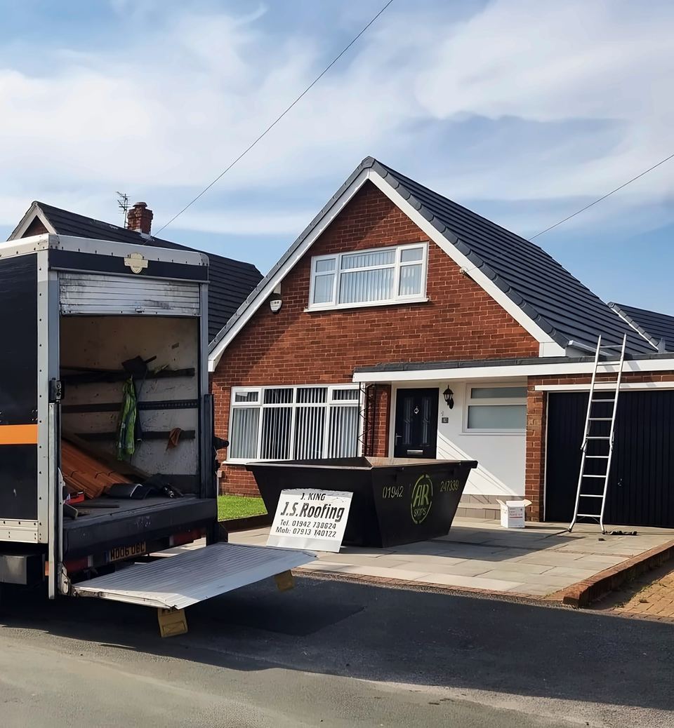 J & S Roofing van and skip outside a job, ladder up to the roof
