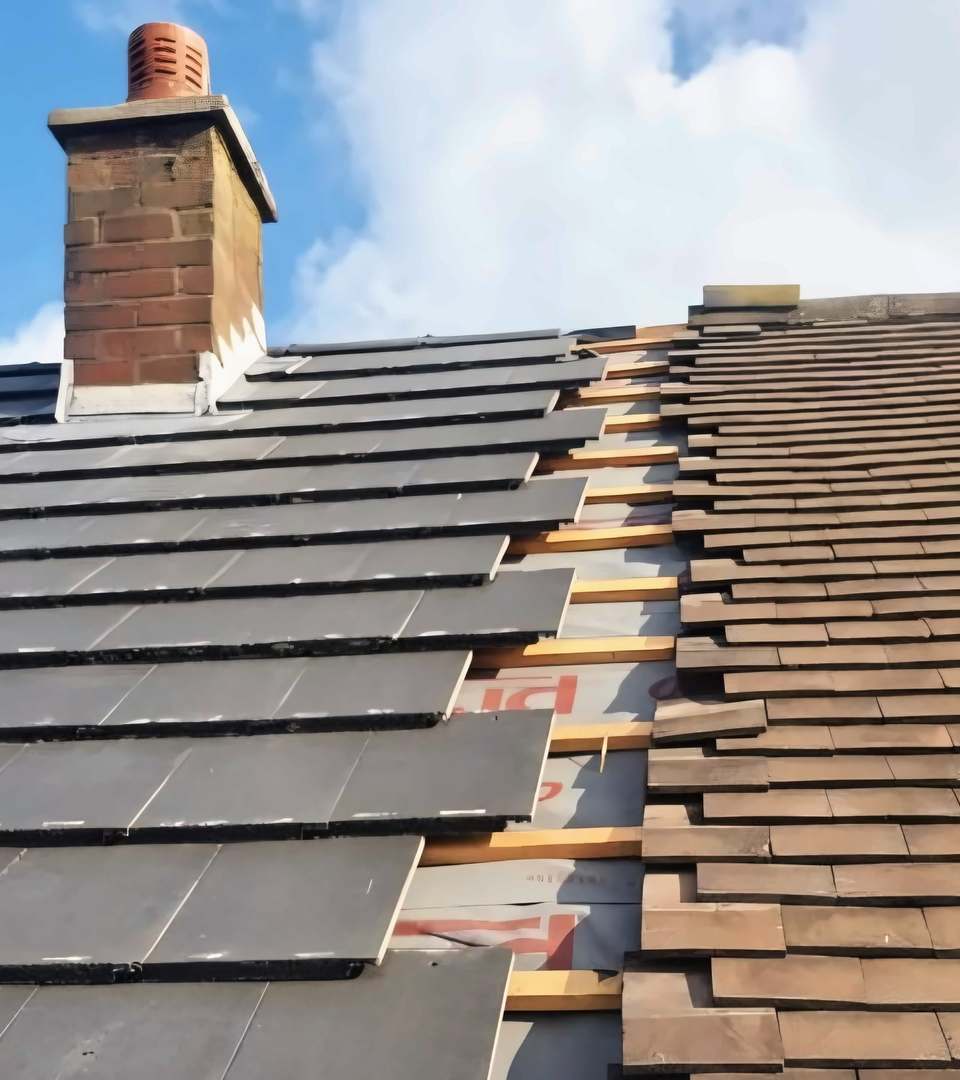New grey tiles going on beside older brown tiles, under a brick chimney