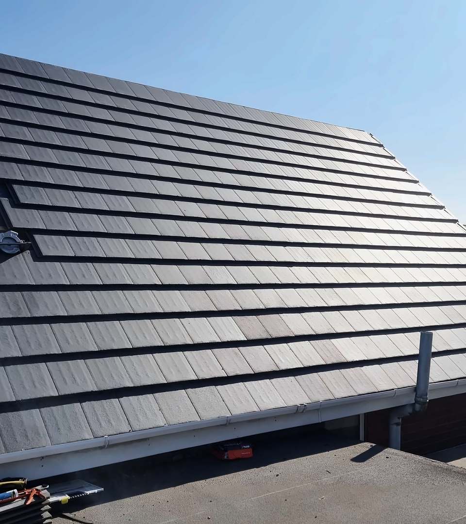 Grey tiles going on over membrane and battens, seen from the flat roof alongside