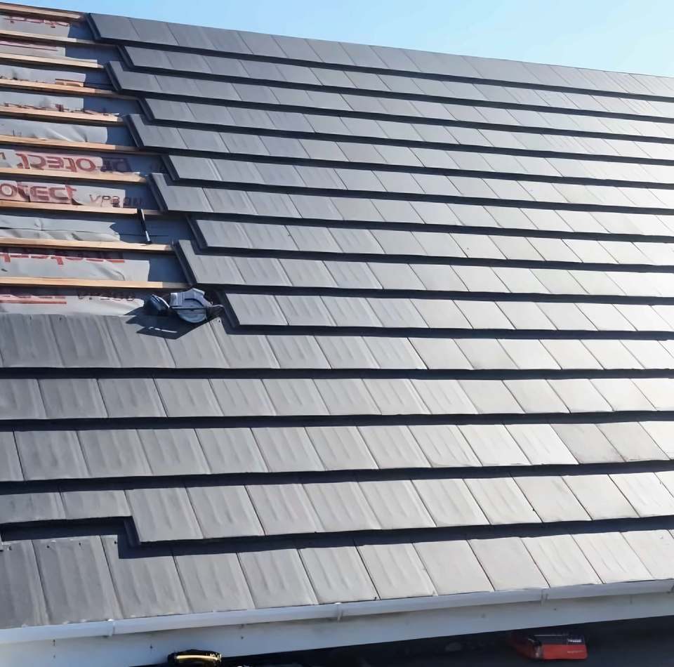 The same roof from the gable end: membrane, battens, grey tiles and white fascia